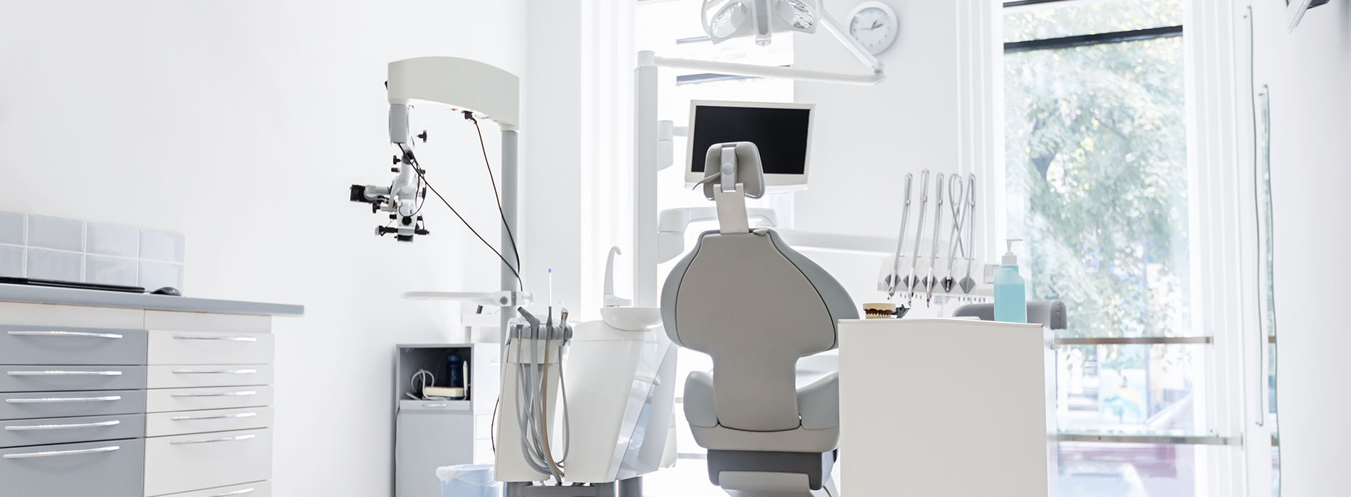 A well-lit reception area with a desk, computer monitor, and potted plant.